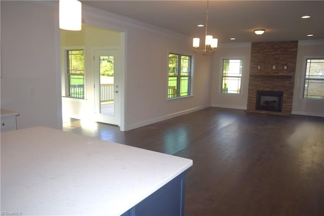 interior space with an inviting chandelier, a fireplace, ornamental molding, baseboards, and dark wood-style floors