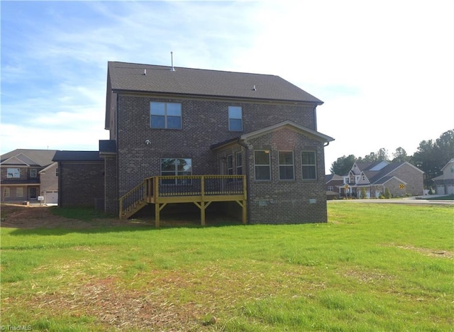 back of property featuring a yard, a deck, and brick siding
