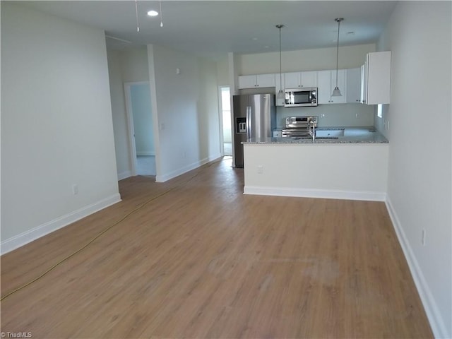 kitchen with appliances with stainless steel finishes, light hardwood / wood-style flooring, light stone countertops, pendant lighting, and white cabinets