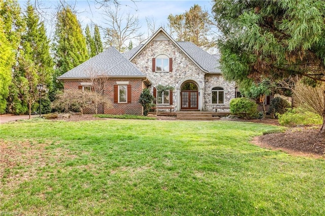 view of front facade with brick siding, stone siding, french doors, and a front yard