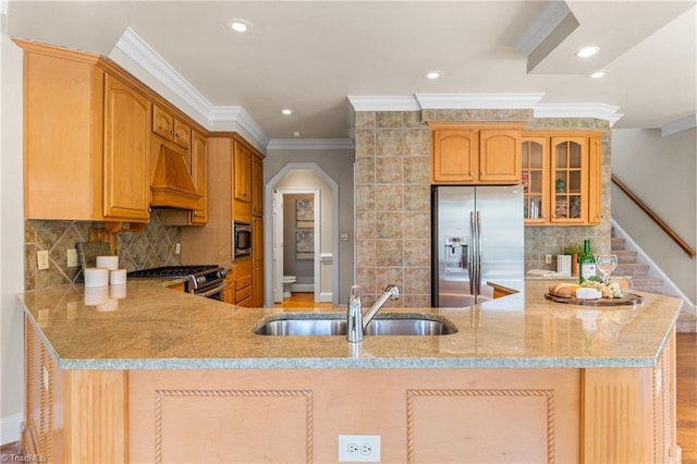 kitchen with glass insert cabinets, light stone countertops, custom exhaust hood, stainless steel appliances, and a sink