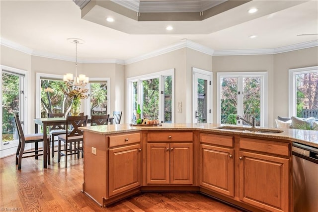 kitchen with wood finished floors, ornamental molding, a sink, stainless steel dishwasher, and a notable chandelier