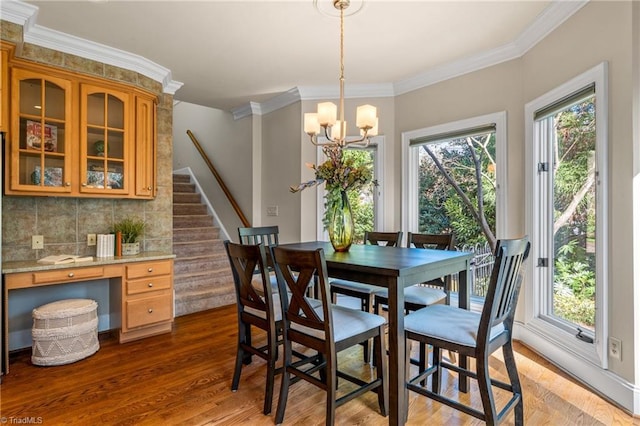 dining room with a wealth of natural light, a notable chandelier, wood finished floors, and ornamental molding