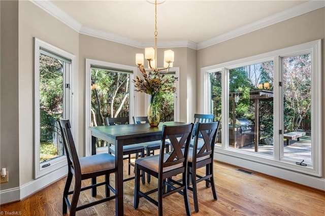 dining room with visible vents, ornamental molding, light wood-style floors, baseboards, and a chandelier