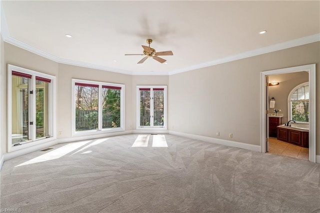 spare room with a wealth of natural light, visible vents, light colored carpet, and ceiling fan