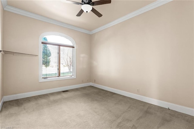 carpeted spare room with visible vents, a ceiling fan, crown molding, and baseboards