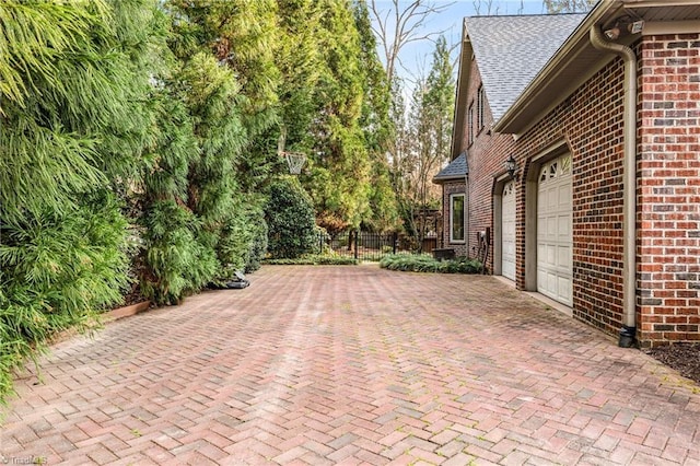 view of patio with decorative driveway, fence, and a garage