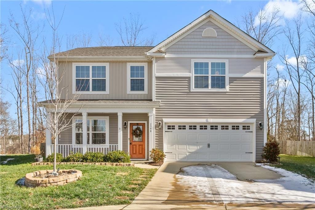 front of property with covered porch, a front yard, and a garage