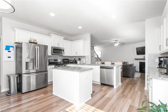 kitchen featuring a center island, white cabinets, decorative backsplash, appliances with stainless steel finishes, and kitchen peninsula