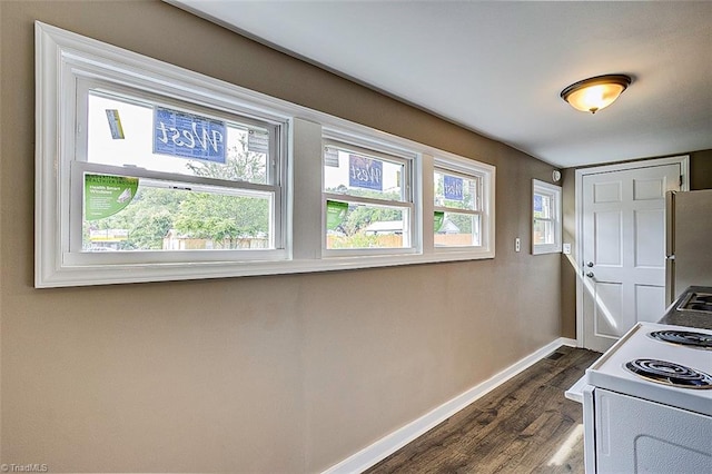 kitchen with a wealth of natural light, electric range, stainless steel fridge, and dark hardwood / wood-style flooring