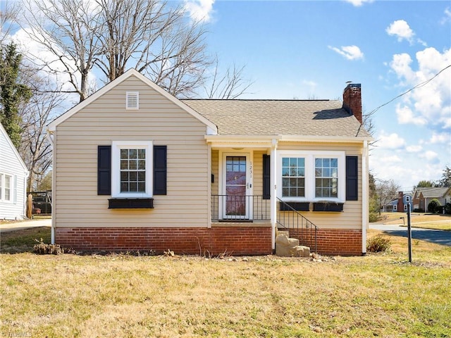 bungalow-style home with a shingled roof, a chimney, and a front lawn