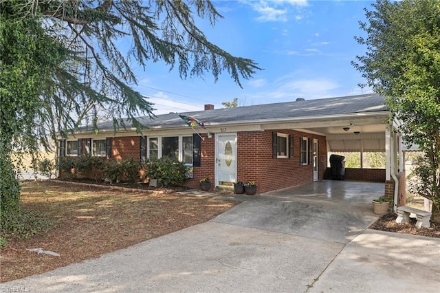 ranch-style home with entry steps, concrete driveway, brick siding, and an attached carport