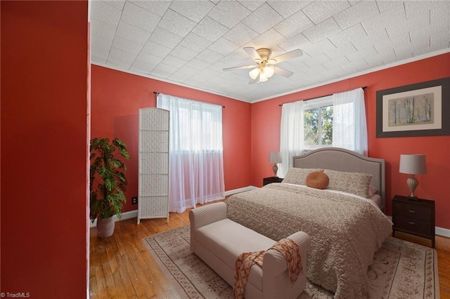 bedroom with baseboards, crown molding, hardwood / wood-style floors, and ceiling fan