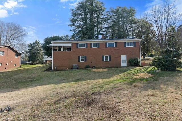 rear view of house with central air condition unit, a lawn, and brick siding