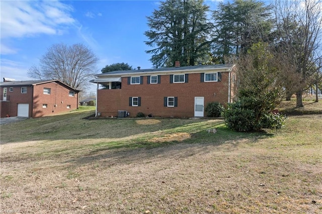 rear view of house featuring a yard, brick siding, a chimney, and central air condition unit