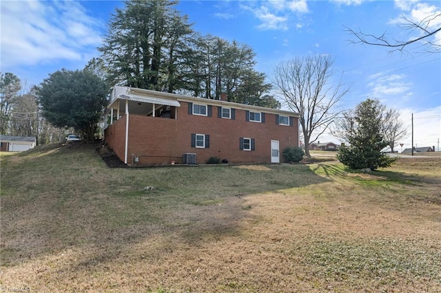 view of property exterior featuring central AC, a yard, a chimney, and brick siding