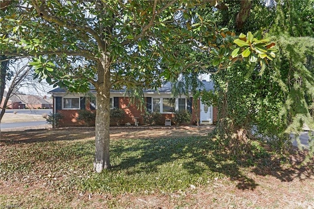 view of property hidden behind natural elements with brick siding