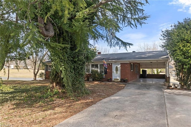 view of front of home with driveway, a carport, and brick siding