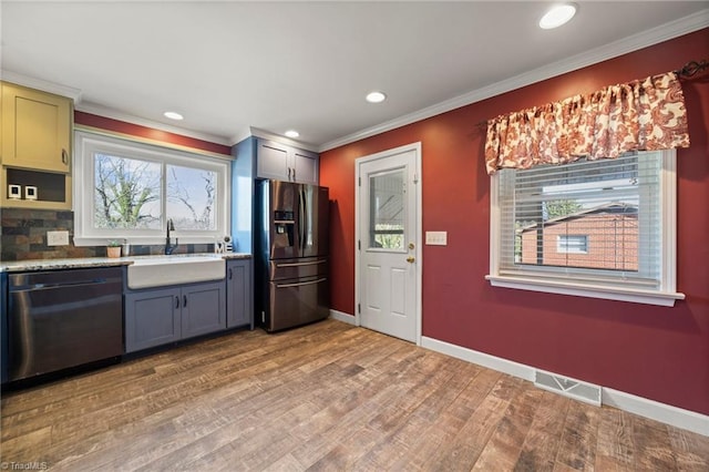 kitchen with light wood-style flooring, a sink, visible vents, stainless steel dishwasher, and black fridge