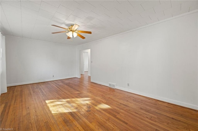 spare room featuring hardwood / wood-style flooring, crown molding, visible vents, and a ceiling fan