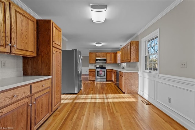 kitchen with sink, light hardwood / wood-style flooring, decorative backsplash, appliances with stainless steel finishes, and ornamental molding