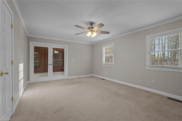 spare room with light carpet, crown molding, ceiling fan, and french doors