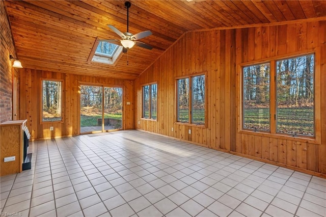 unfurnished sunroom with vaulted ceiling with skylight, ceiling fan, a healthy amount of sunlight, and wood ceiling