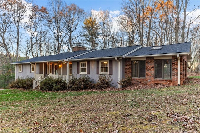 ranch-style home featuring covered porch and a front lawn