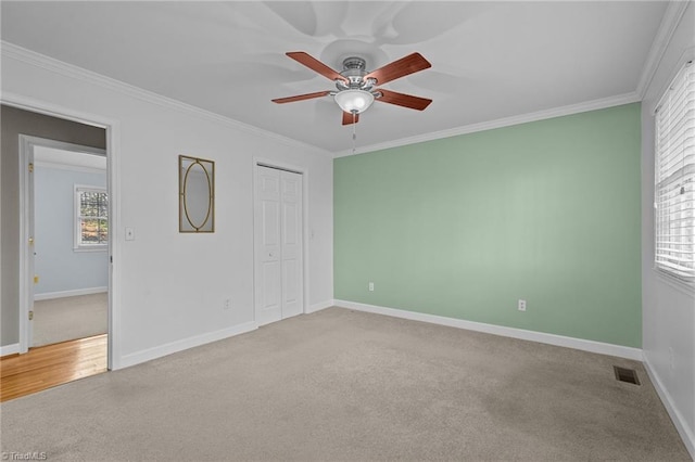 unfurnished bedroom featuring ceiling fan, light colored carpet, and ornamental molding