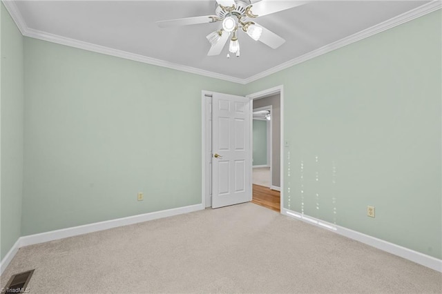 carpeted spare room with ceiling fan and crown molding