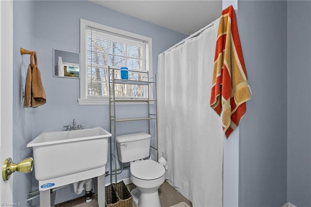 bathroom featuring a shower with shower curtain, toilet, and sink