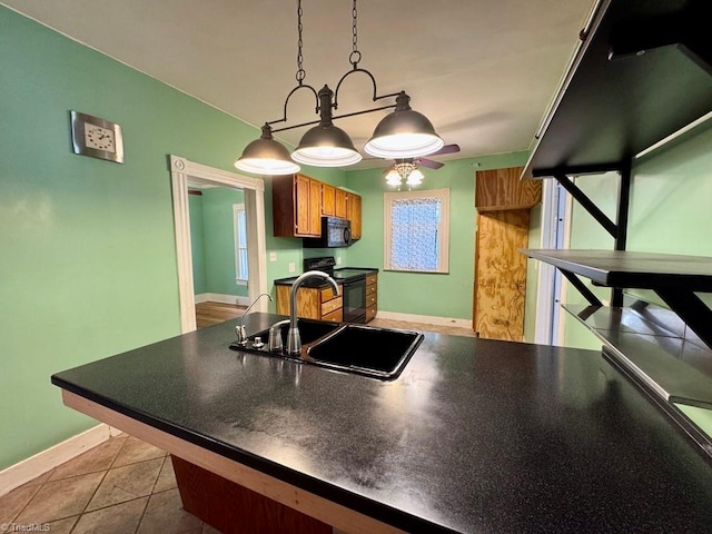 kitchen featuring light tile patterned flooring, sink, hanging light fixtures, and black appliances