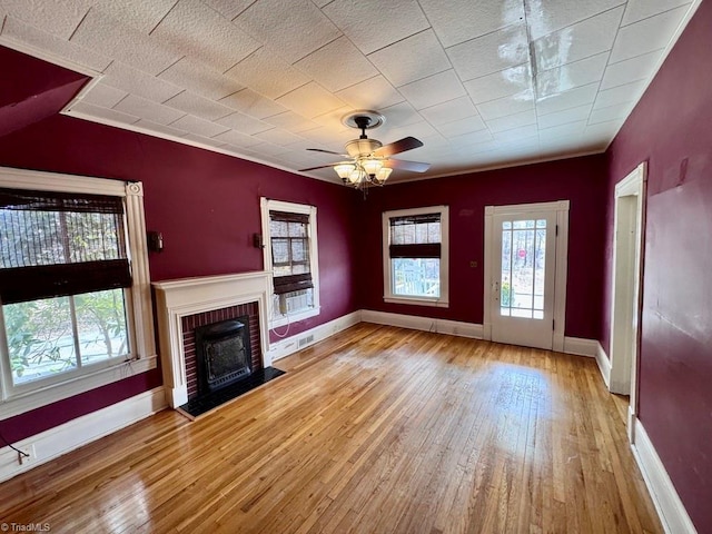 unfurnished living room featuring ceiling fan, a healthy amount of sunlight, a fireplace, and light hardwood / wood-style floors