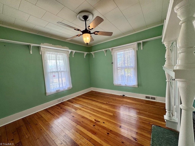 unfurnished room featuring hardwood / wood-style flooring, ceiling fan, and crown molding