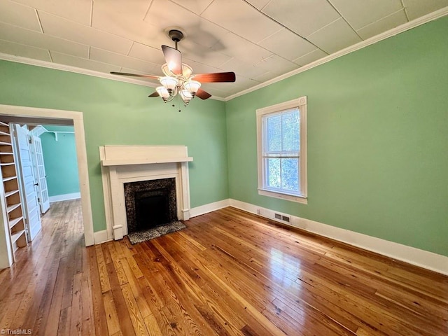 unfurnished living room featuring hardwood / wood-style flooring, a fireplace, ornamental molding, and ceiling fan