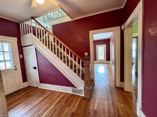 stairs featuring hardwood / wood-style flooring, crown molding, and a wealth of natural light