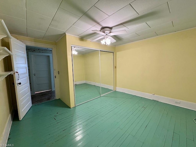 unfurnished bedroom featuring ornamental molding, hardwood / wood-style floors, ceiling fan, and a closet