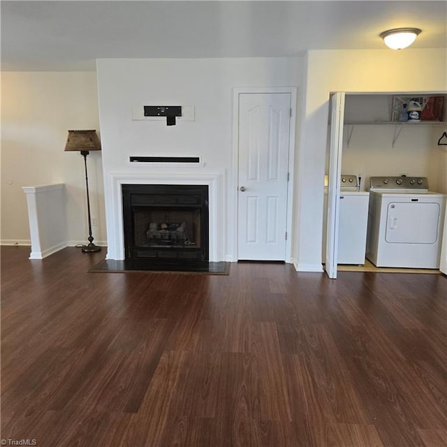 unfurnished living room with washing machine and dryer, dark wood-style flooring, baseboards, and a fireplace with flush hearth