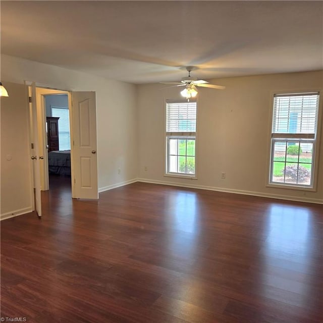 spare room featuring baseboards, ceiling fan, and dark wood-style floors