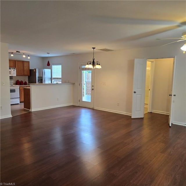 unfurnished living room with baseboards, dark wood-style flooring, visible vents, and ceiling fan with notable chandelier