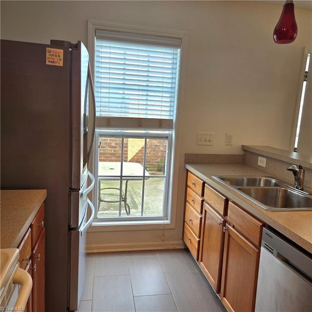 kitchen featuring appliances with stainless steel finishes, light tile patterned floors, a healthy amount of sunlight, and a sink