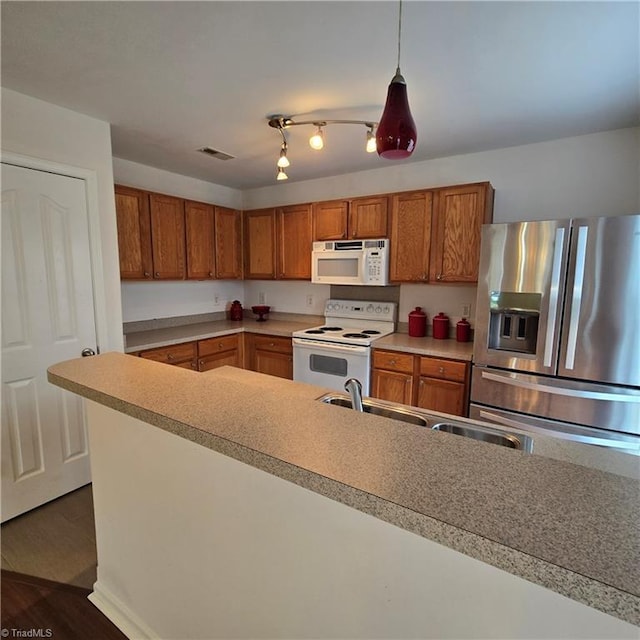 kitchen with white appliances, visible vents, a sink, brown cabinets, and light countertops