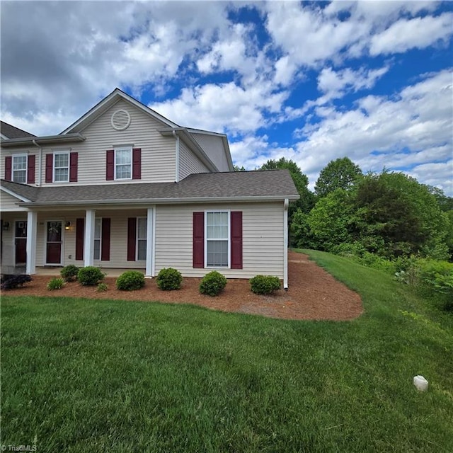 view of front of property with a front yard, roof with shingles, and covered porch