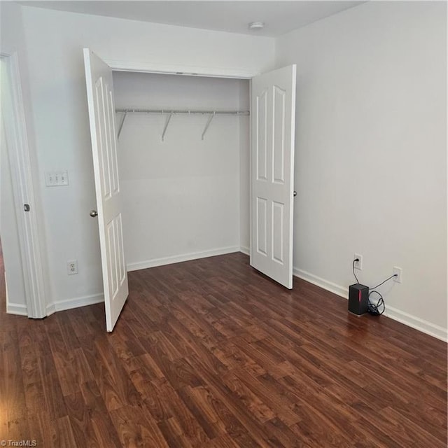 unfurnished bedroom featuring a closet, baseboards, and dark wood-style floors