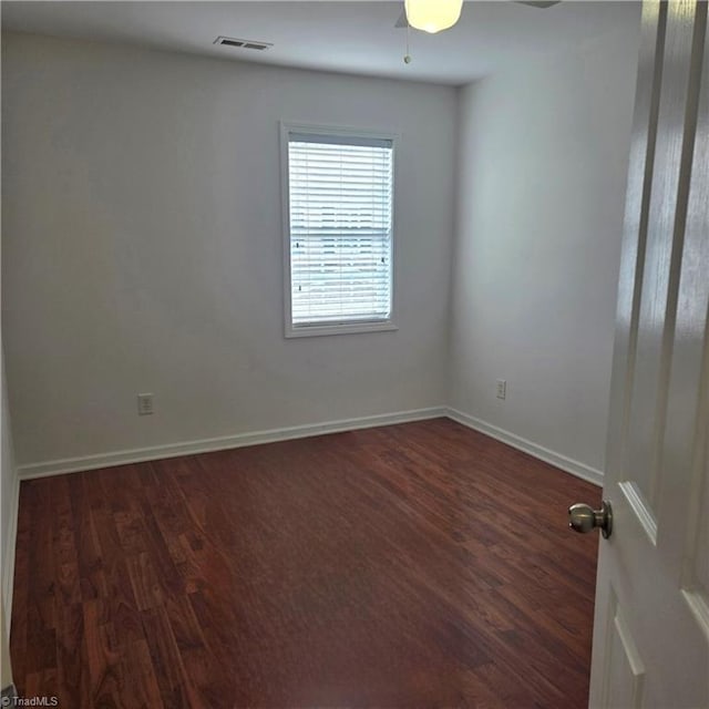empty room with baseboards, dark wood-style floors, and visible vents