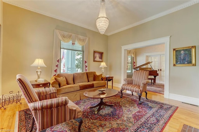 living room with hardwood / wood-style floors, an inviting chandelier, french doors, and ornamental molding