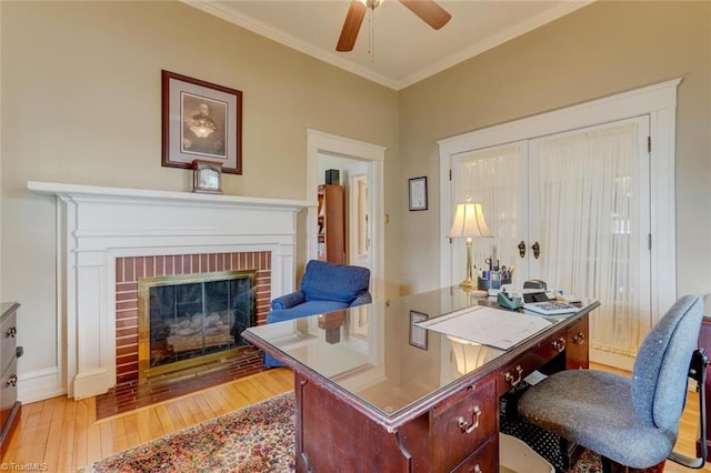 home office with ceiling fan, crown molding, a fireplace, and light hardwood / wood-style flooring