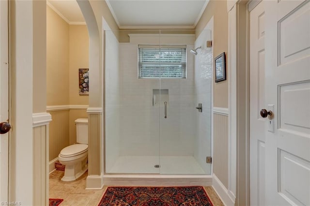 bathroom with a shower with shower door, toilet, and ornamental molding