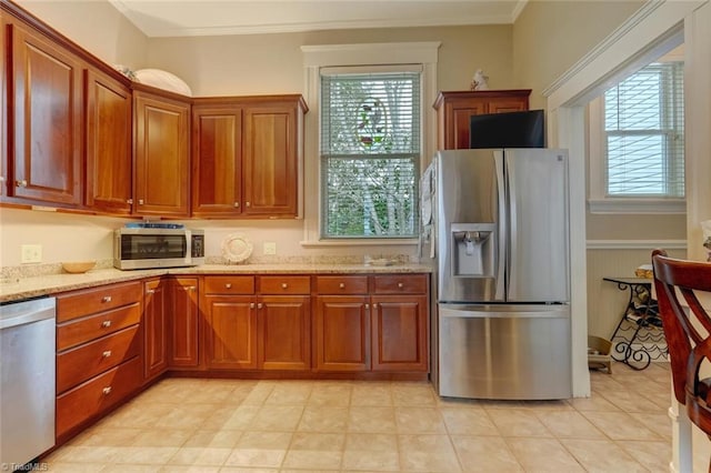 kitchen featuring stainless steel appliances, light stone counters, plenty of natural light, and ornamental molding