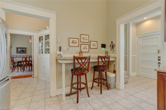 bar with light stone countertops, white fridge, and light tile patterned flooring